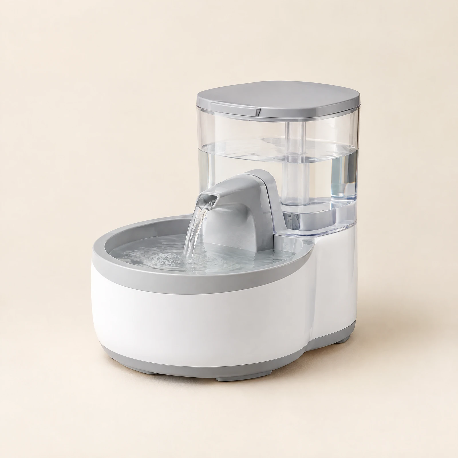 A white and light gray pet water fountain with a clear tank, a flowing spout and a round drinking basin, on a cream background